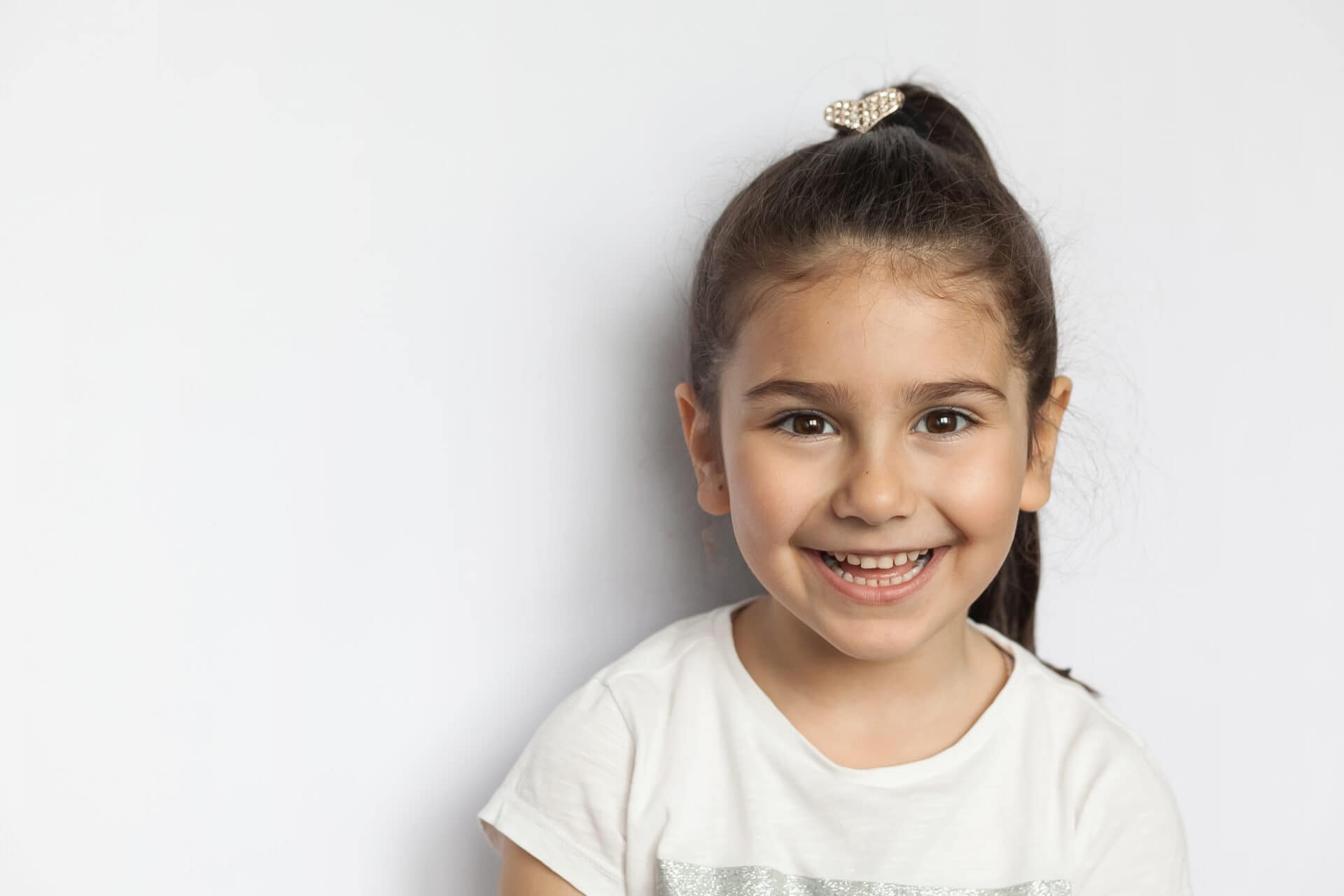 Portrait of happy cute brunette child girl on white background